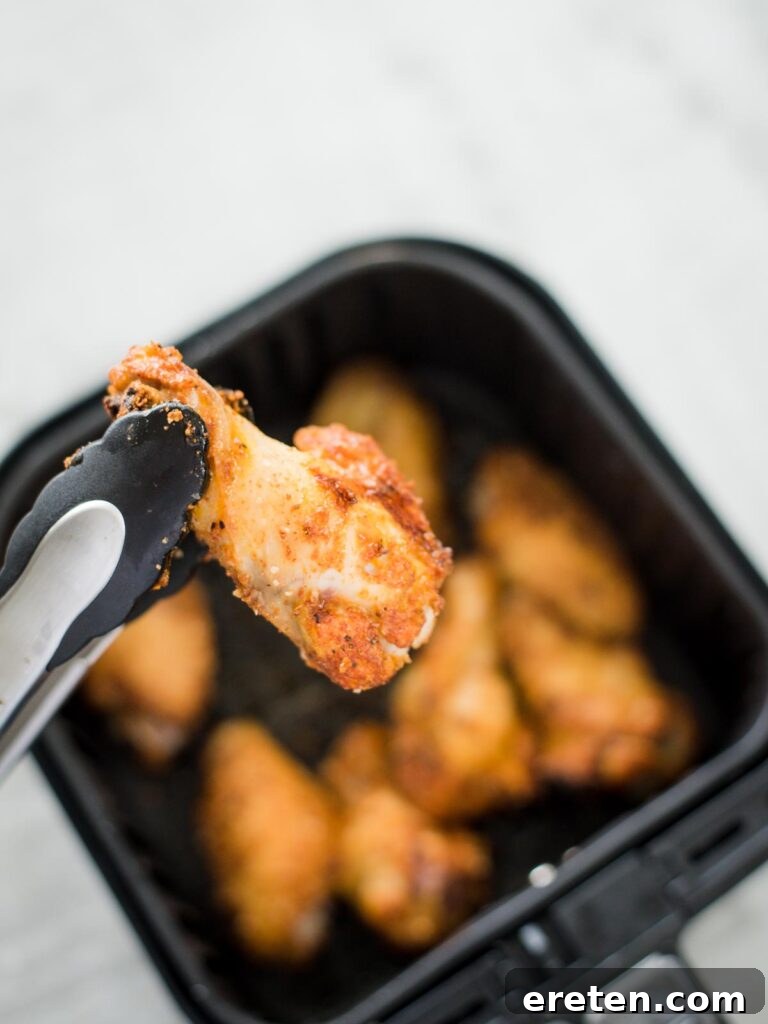 Crispy Air Fryer Dry Rub Wings 7 turning chicken wings over in the air fryer basket
