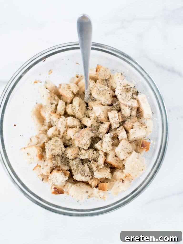 Bread in a mixing bowl with seasoning, thoroughly mixed