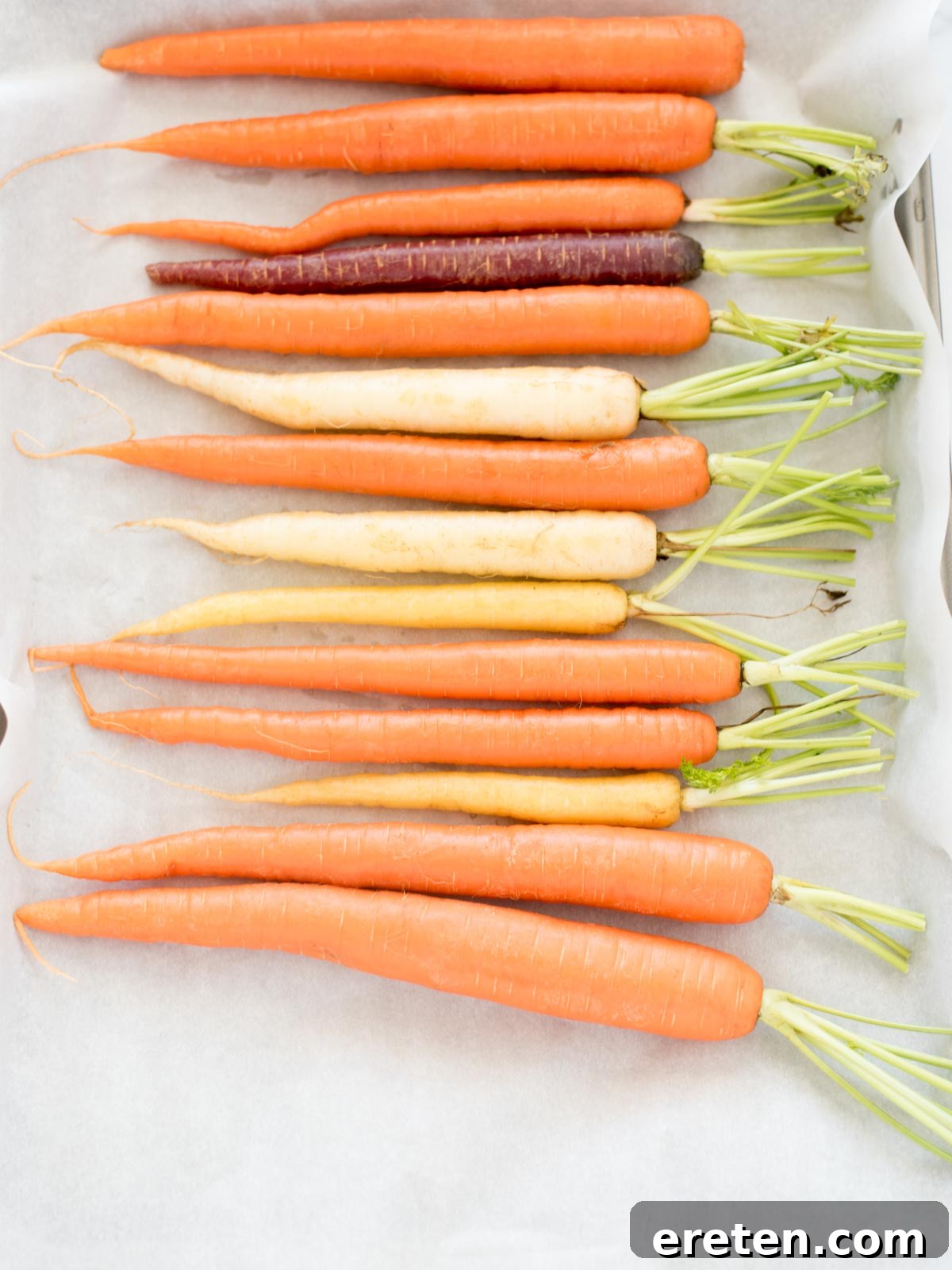 Golden Brown Sugar Glazed Carrots 6 Carrots arranged on a parchment-lined baking sheet before glazing.