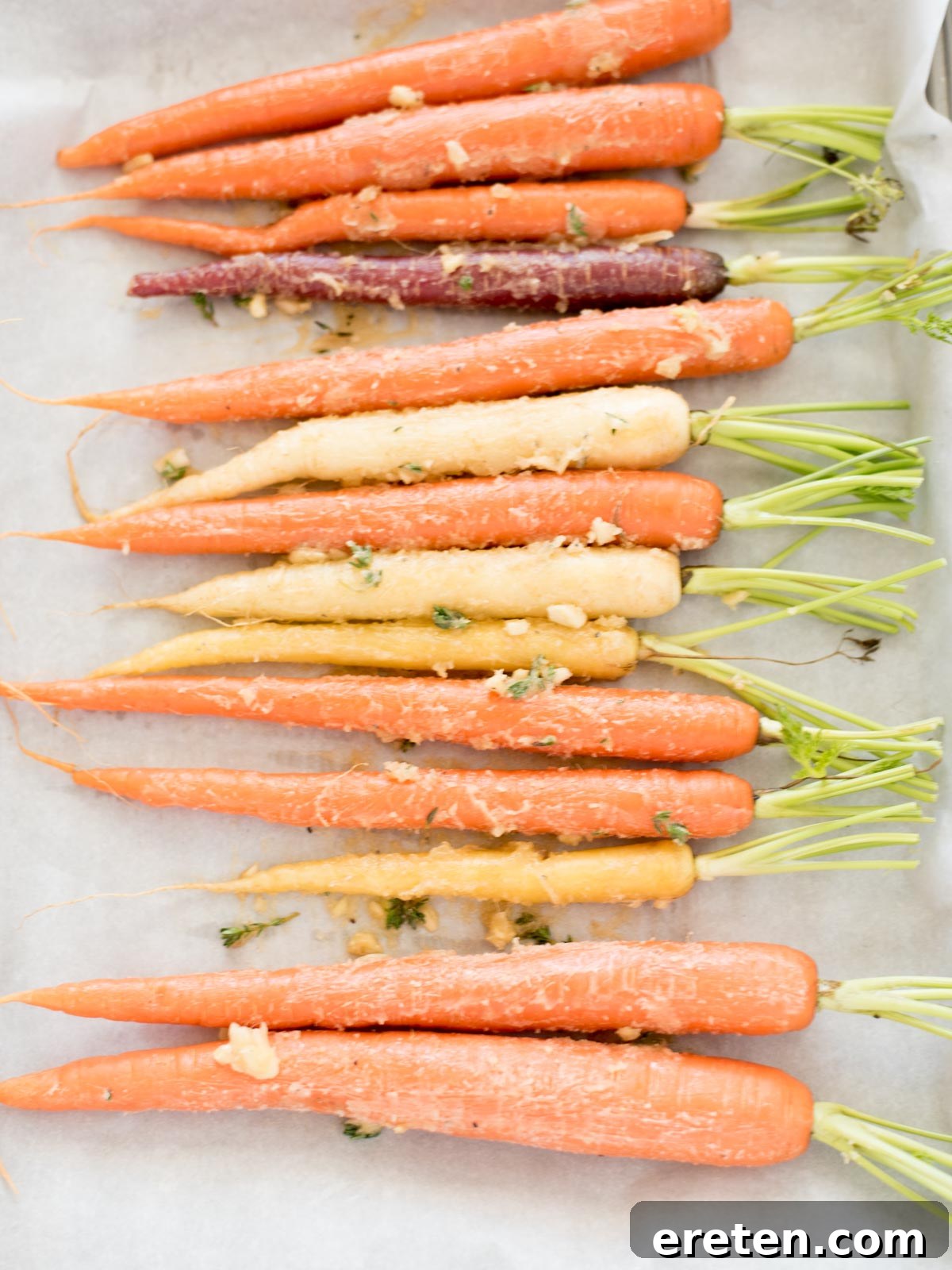 Golden Brown Sugar Glazed Carrots 7 Carrots evenly coated in brown sugar garlic glaze on baking sheet.