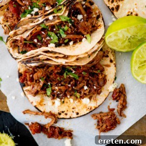 mexican shredded beef inside tacos topped with cilantro and queso fresco