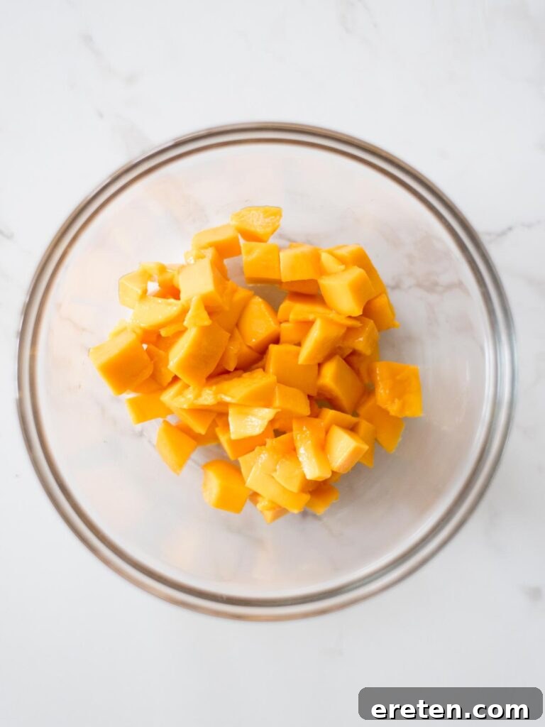 Diced fresh mango pieces in a glass mixing bowl, ready for salsa.