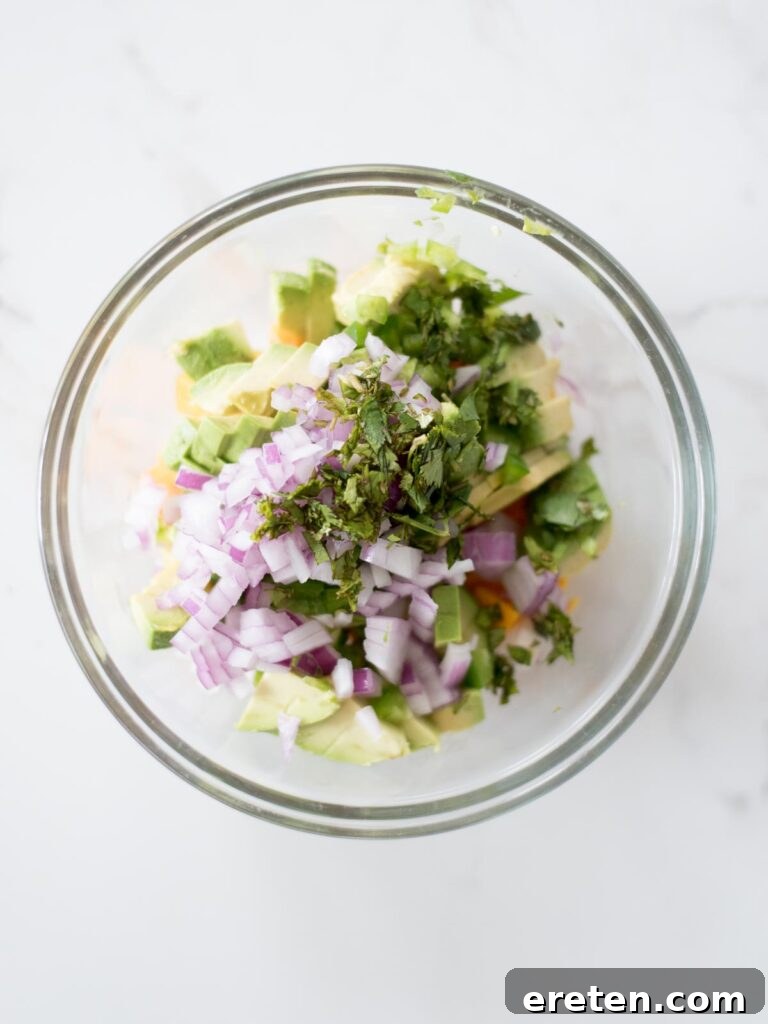 Freshly chopped cilantro sprinkled into the mixing bowl with salsa ingredients.