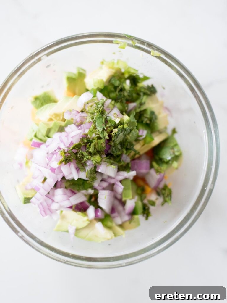 Fresh lime juice being squeezed over the ingredients in the mixing bowl for avocado mango salsa.