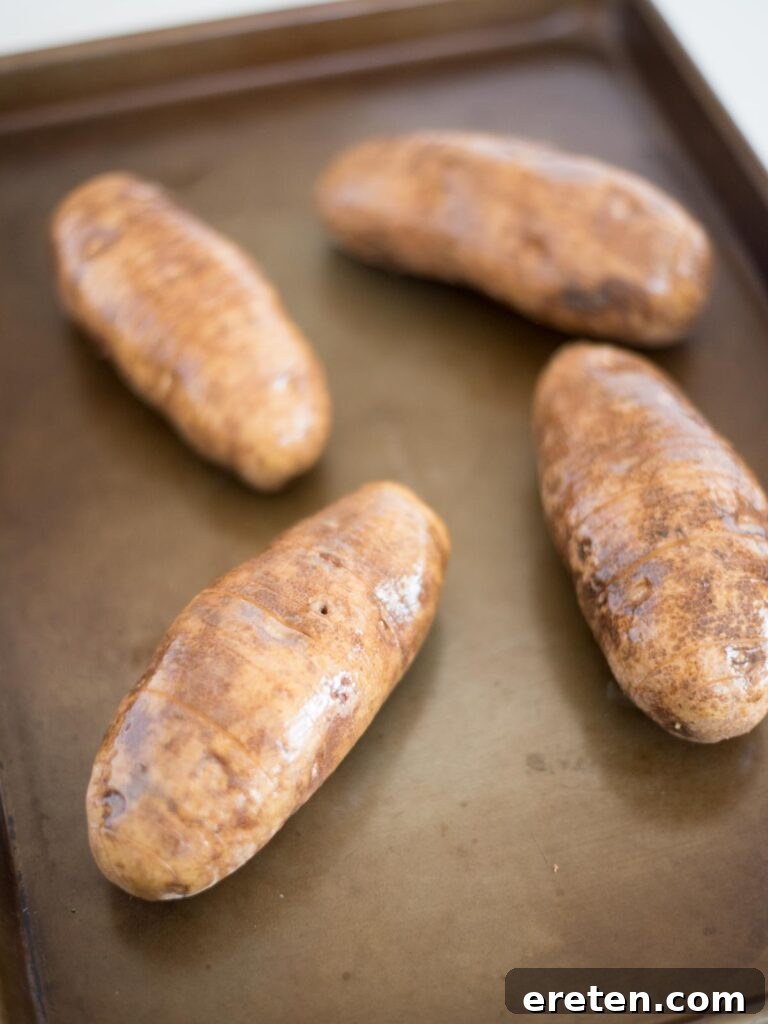 a pastry brush applying melted butter onto the surface of a sliced hasselback potato