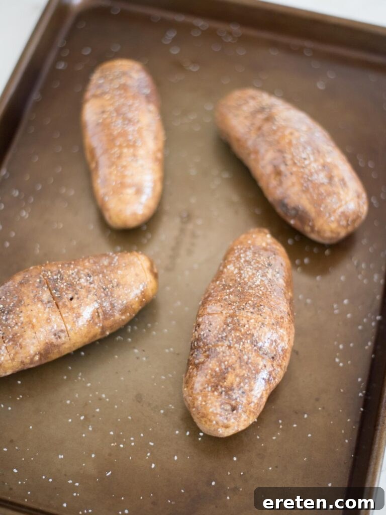 a sliced hasselback potato seasoned with salt, pepper, and butter, prepared for baking