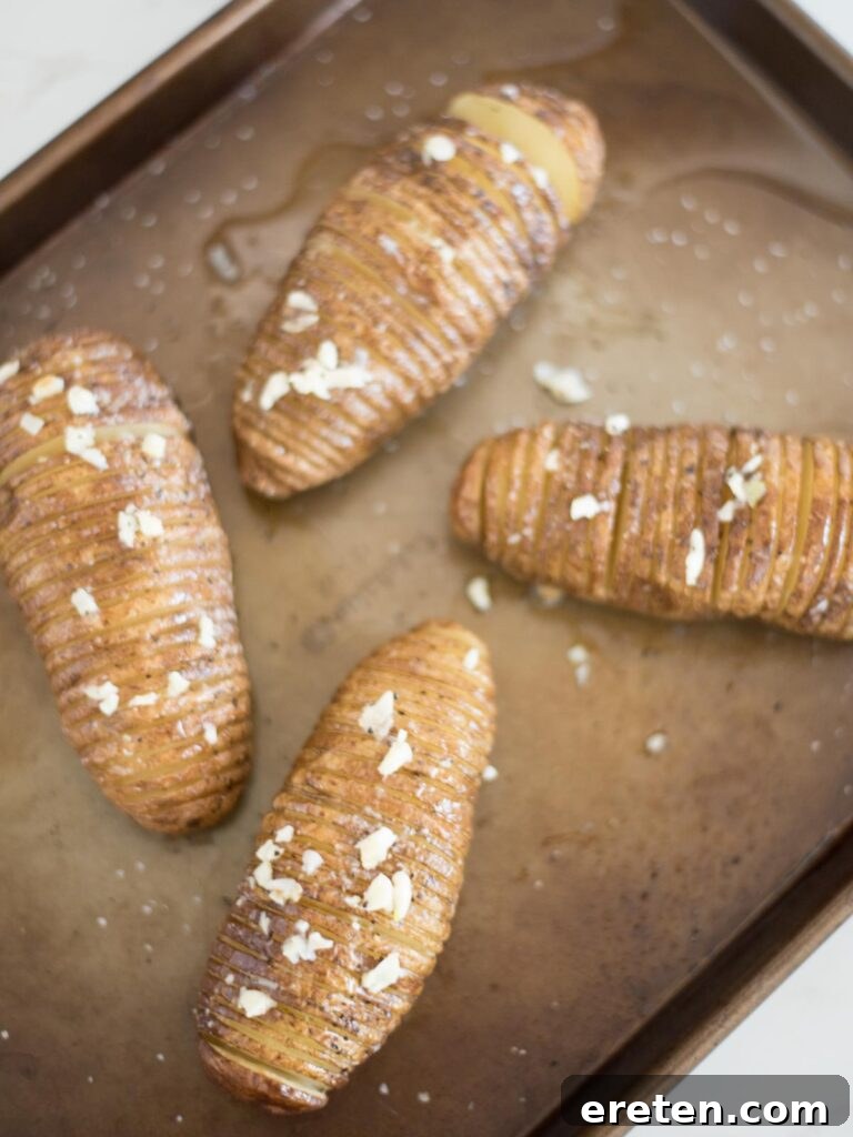 fragrant garlic butter being brushed over the fanned slices of baked hasselback potatoes