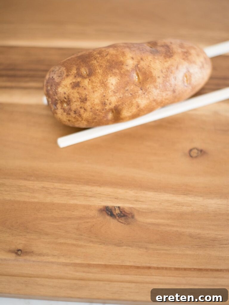 russet potato positioned on chopsticks, ready for precise slicing