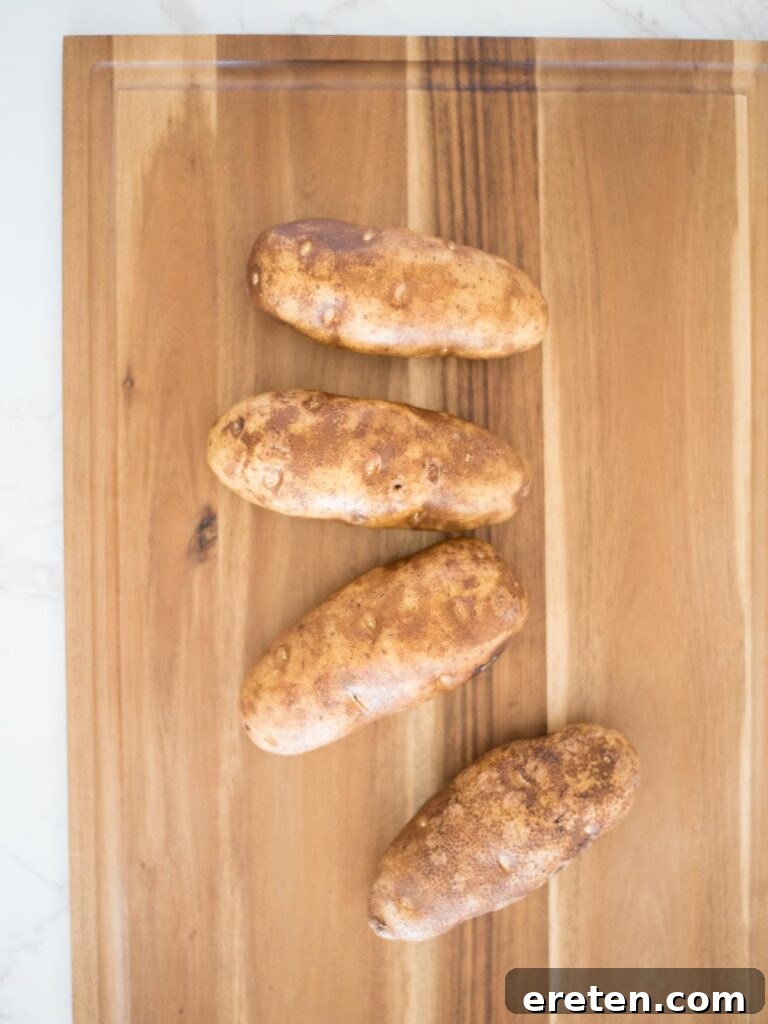 washed russet potatoes on a cutting board, prepared for the Hasselback slicing process