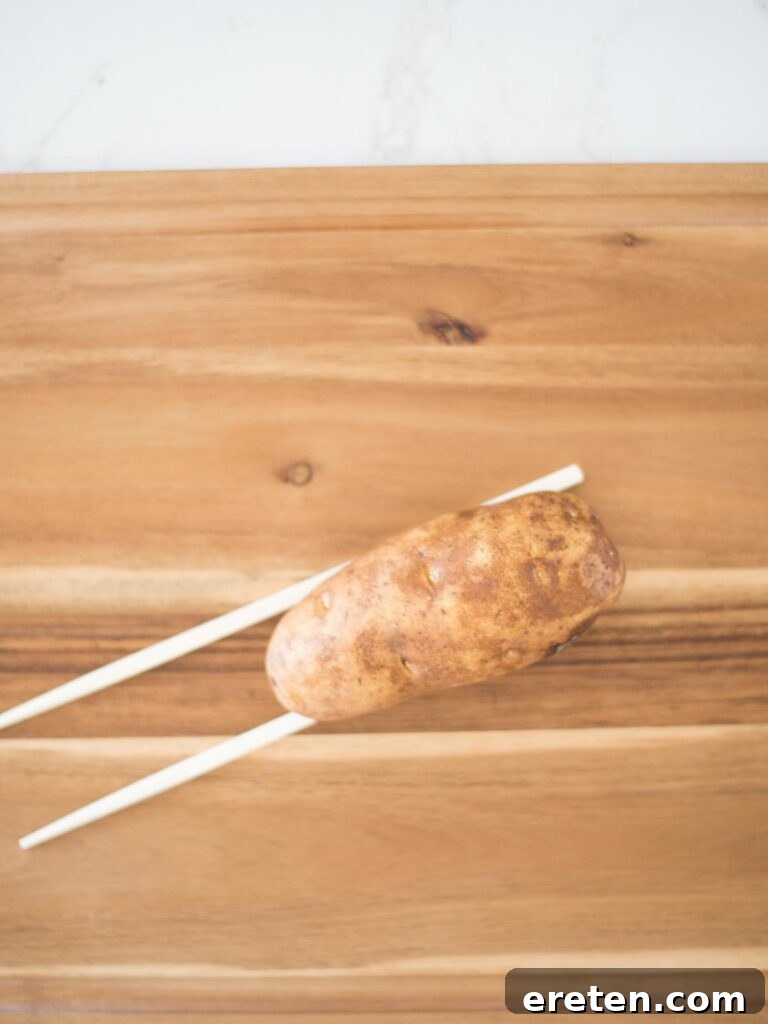 russet potato carefully placed on chopsticks as a guide for cutting