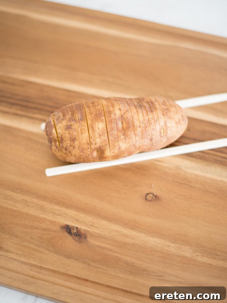 precisely sliced hasselback potato on chopsticks, demonstrating the successful cuts