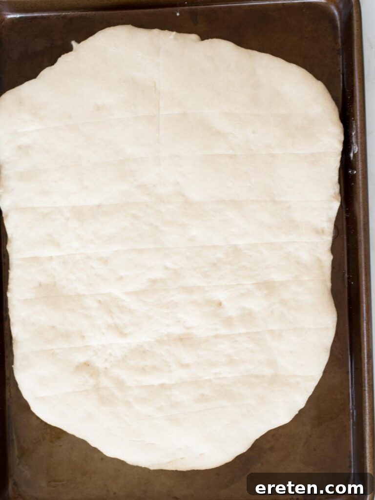 scored bread dough, visibly risen on a baking sheet