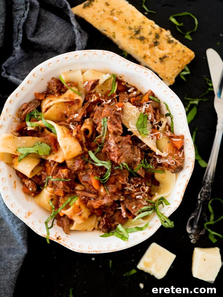 beef ragu over pasta topped with basil and parmesan