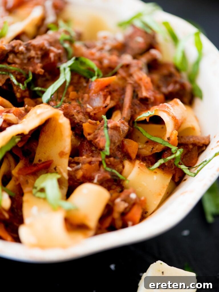 beef ragu over pasta topped with basil and parmesan