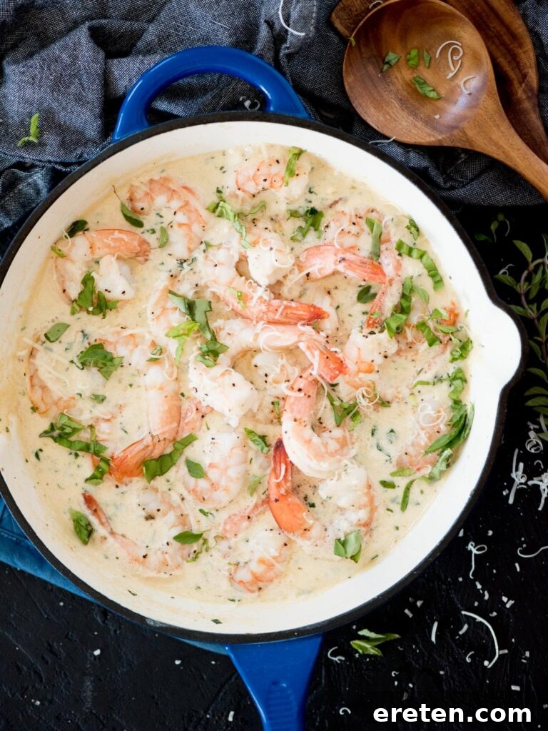 A vibrant blue enamel cast iron skillet brimming with creamy garlic shrimp and freshly grated Parmesan, ready to serve.