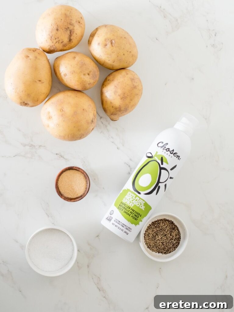 Fresh ingredients laid out for crispy oven baked garlic potato wedges including yukon gold potatoes, garlic powder, salt, and avocado oil spray.