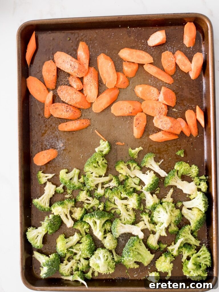 partially roasted broccoli and carrots on a sheet pan