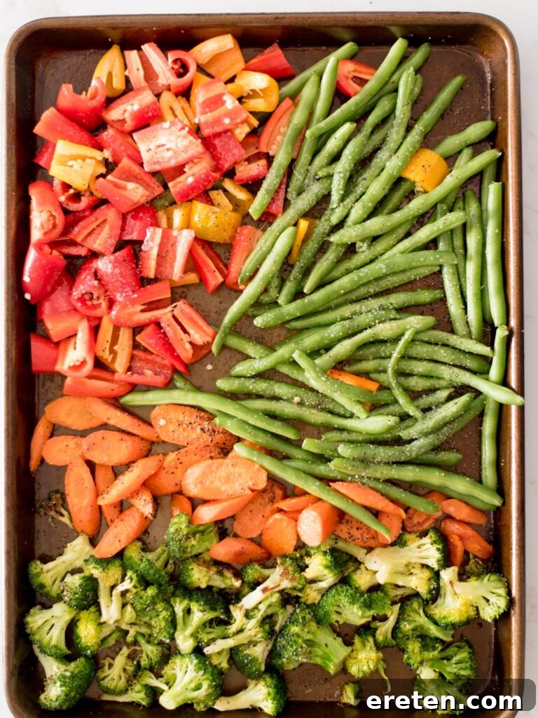 bell pepper, green beans, carrots, and broccoli on a sheet pan seasoned with salt and pepper