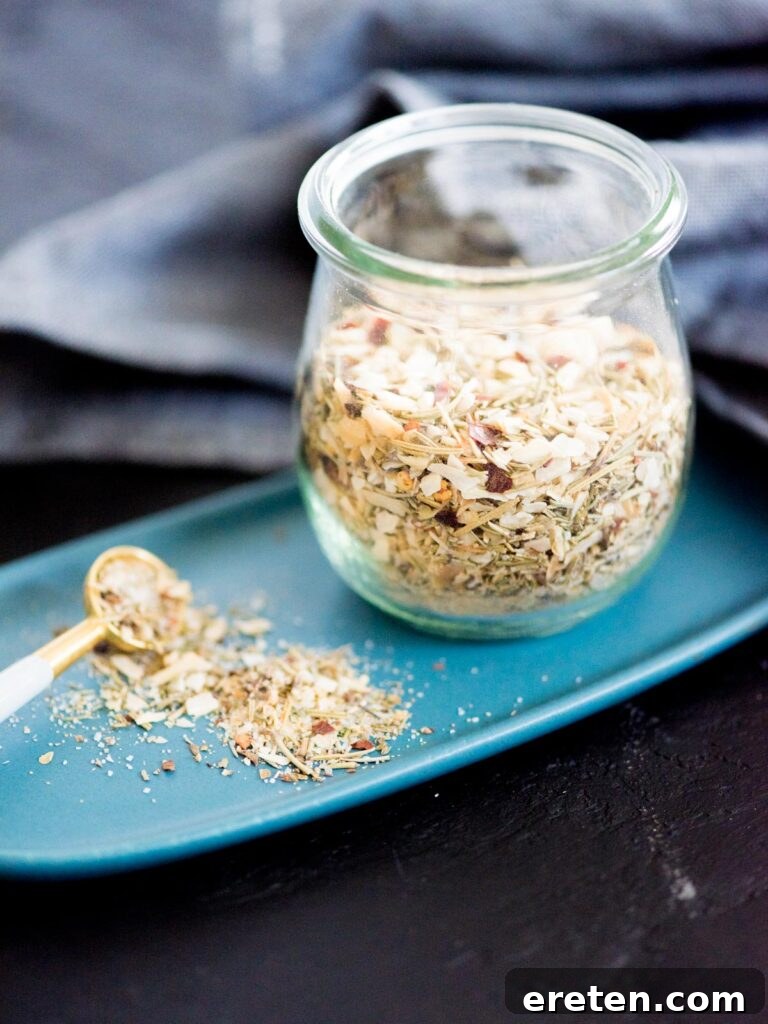Rustic Tuscan Herb Mix 2 A jar of homemade Tuscan herb seasoning blend, a measuring spoon, and a small white plate, ready for culinary use.