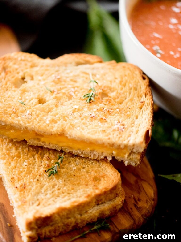 Air Fryer Grilled Cheese Perfection 10 A delectable air fried grilled cheese sandwich, expertly cut in half, positioned beside a steaming bowl of vibrant tomato basil soup, elegantly garnished with a delicate sprig of fresh thyme, ready to be enjoyed.