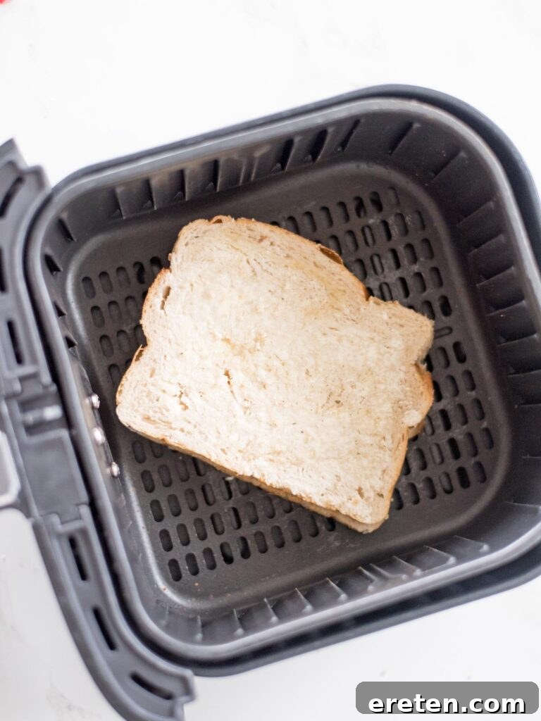 Air Fryer Grilled Cheese Perfection 8 An uncooked cheese sandwich, with buttered bread and cheese layers, sitting neatly inside an air fryer basket, ready to be cooked.