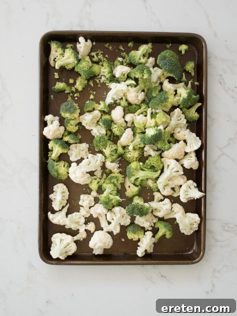 Broccoli and cauliflower florets spread on a sheet pan before seasoning.