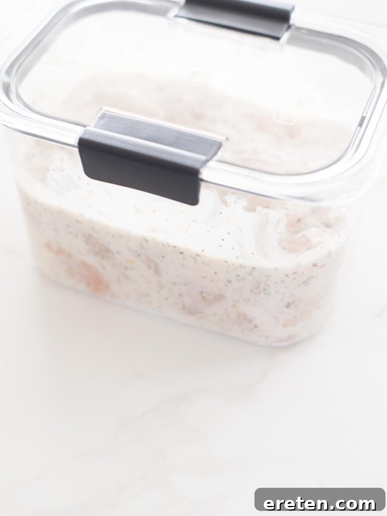 Marinating chicken and Greek yogurt in an airtight container for refrigeration.