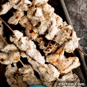 Greek grilled chicken skewers stacked together with tzatziki sauce