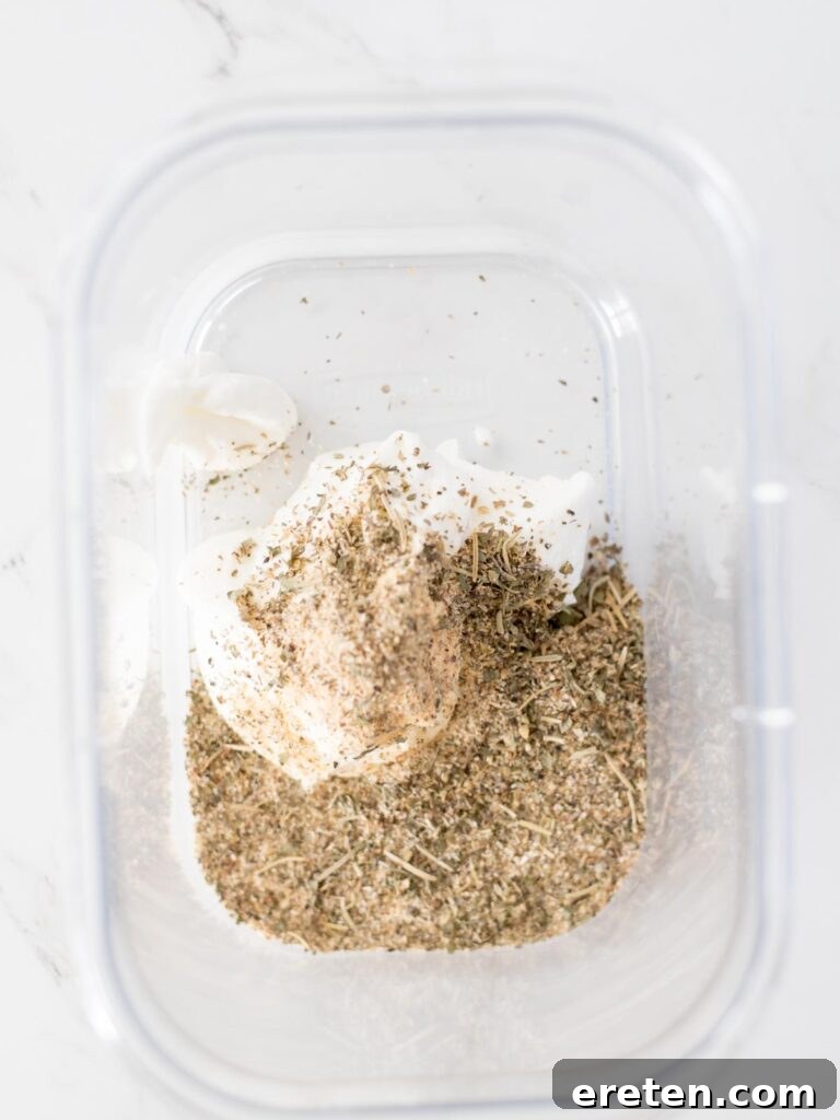 Greek seasoning added to a bowl of yogurt, forming the base of the marinade.