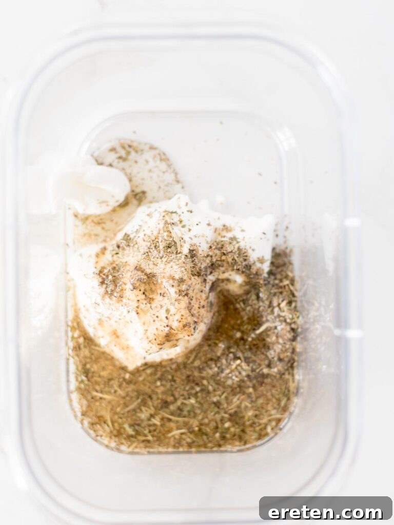 Olive oil being poured into the bowl with yogurt and Greek seasoning.