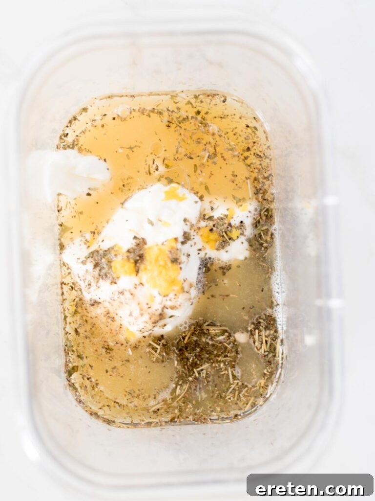Fresh lemon juice joining the olive oil, yogurt, and Greek seasoning in the bowl.