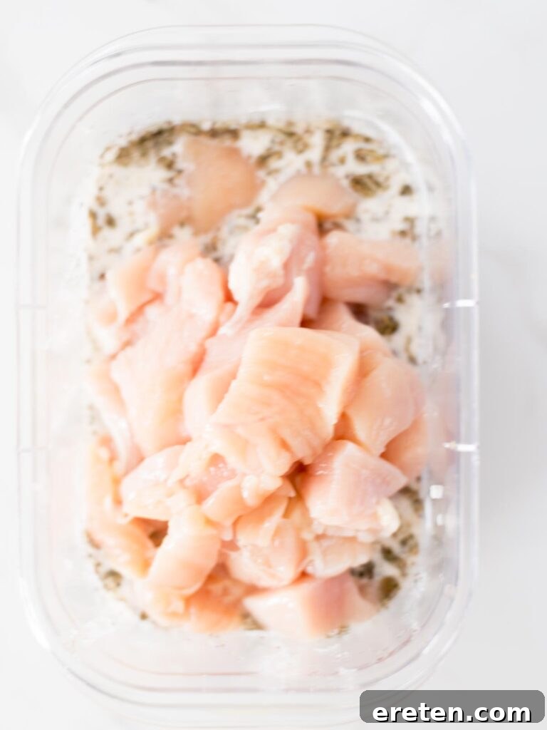 Cubed chicken breast added to the bowl, ready to be coated in the Greek marinade.