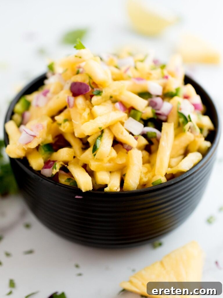 Tropical Pineapple Salsa 2 Freshly prepared pineapple pico de gallo in a sleek black bowl, garnished with cilantro, ready to be served