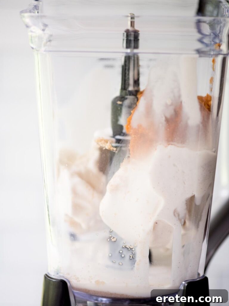 A spoonful of rich brown sugar being added to the blender, enhancing the sweetness and depth of the pumpkin milkshake.