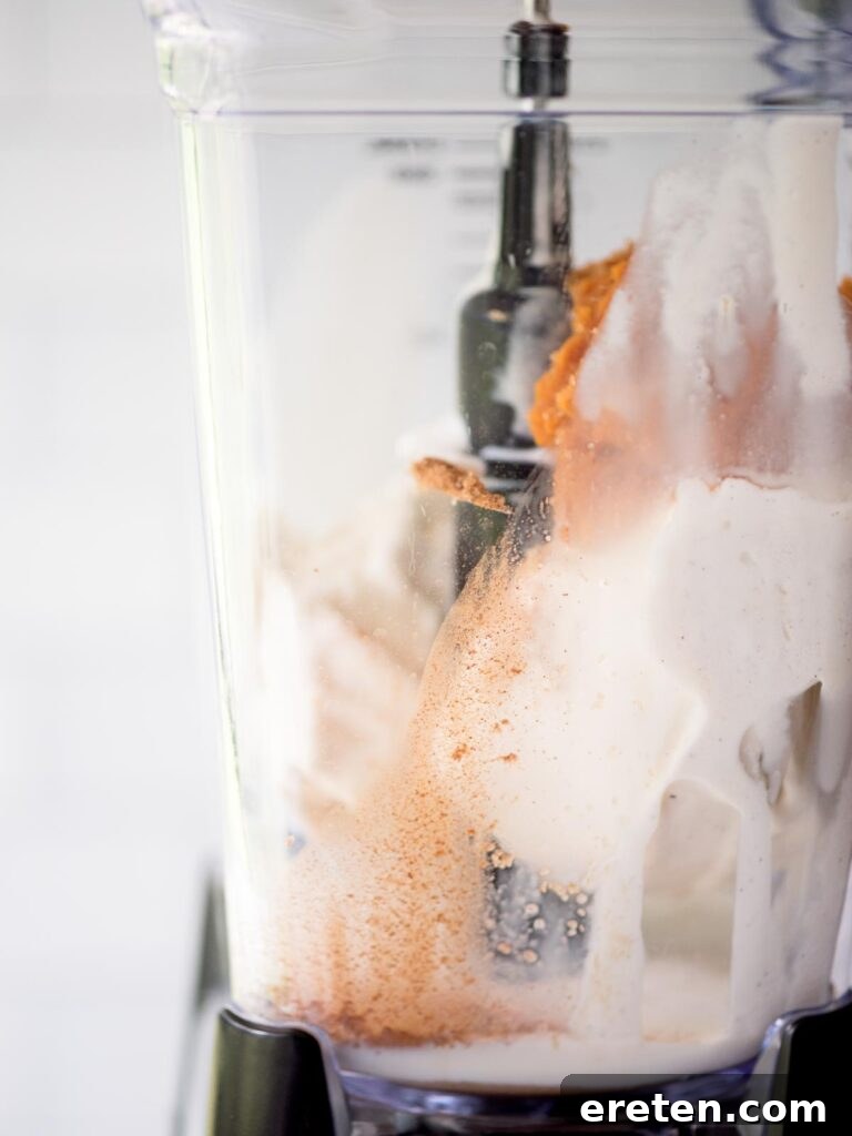 Fragrant pumpkin pie spice being sprinkled into the blender, crucial for the signature fall taste of the milkshake.