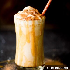 A creamy pumpkin milkshake in a glass, topped with whipped cream and caramel drizzle, ready to be enjoyed.