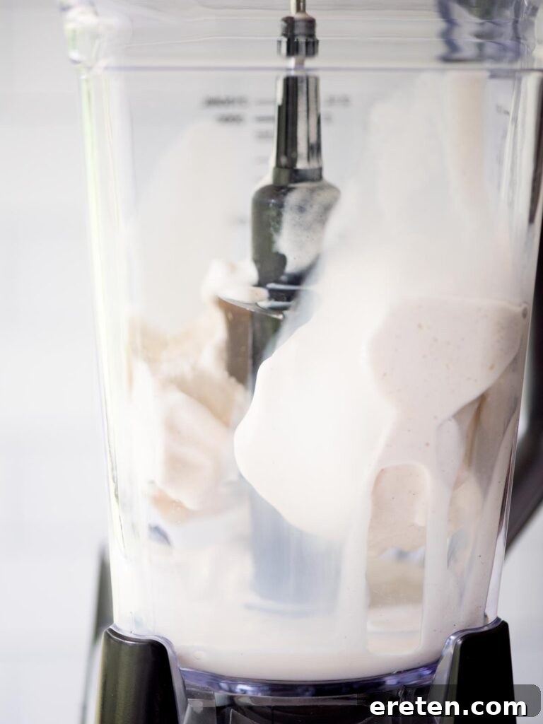 Vanilla ice cream and fresh milk being added to a blender, forming the liquid base for the pumpkin shake.