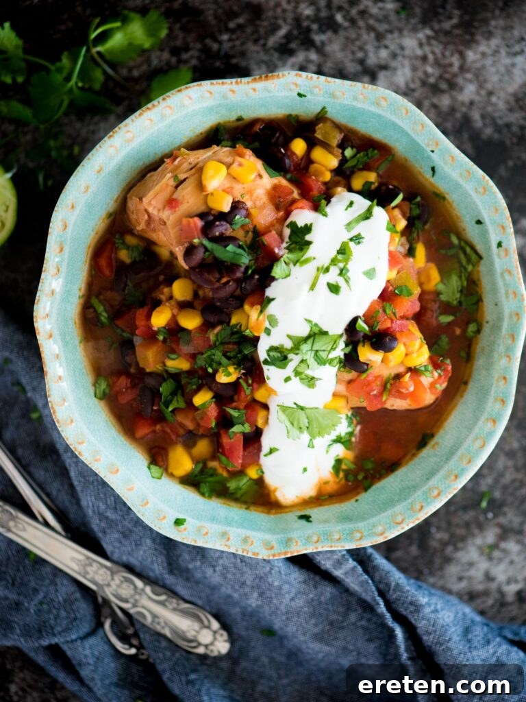 Easy Slow Cooker Mexican Chicken 2 A bowl of slow cooker Mexican chicken topped with fresh cilantro and a dollop of sour cream, ready to serve.