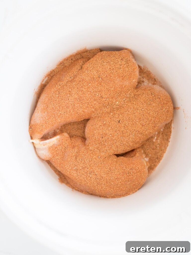 Easy Slow Cooker Mexican Chicken 5 Taco seasoning generously sprinkled over chicken in the crockpot.