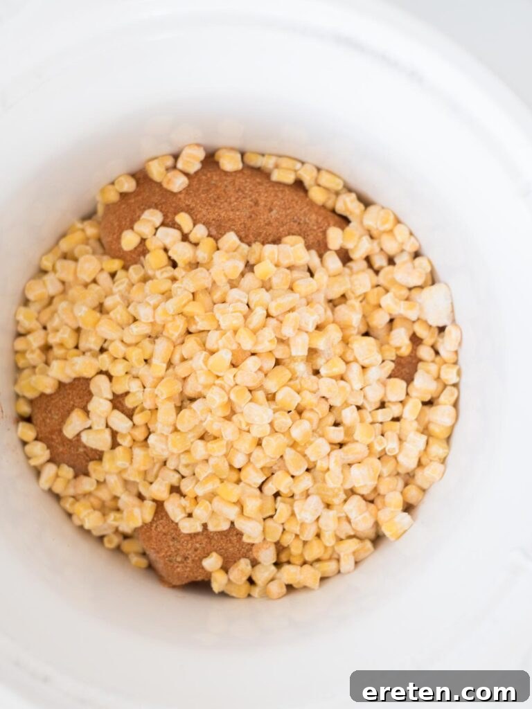 Easy Slow Cooker Mexican Chicken 6 Frozen corn being added to the slow cooker with chicken and seasoning.