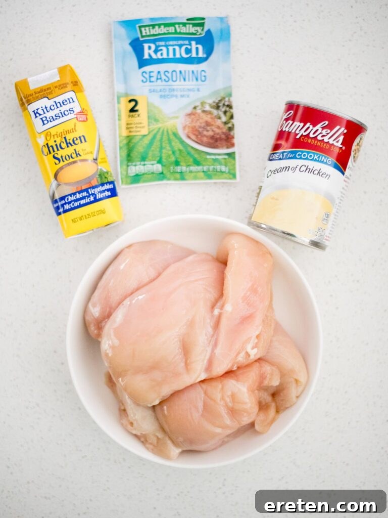 Creamy Ranch Slow Cooker Chicken 3 All four simple ingredients laid out for Crockpot Ranch Chicken preparation: dry ranch mix, boneless chicken breasts, cream of chicken soup, and chicken stock.