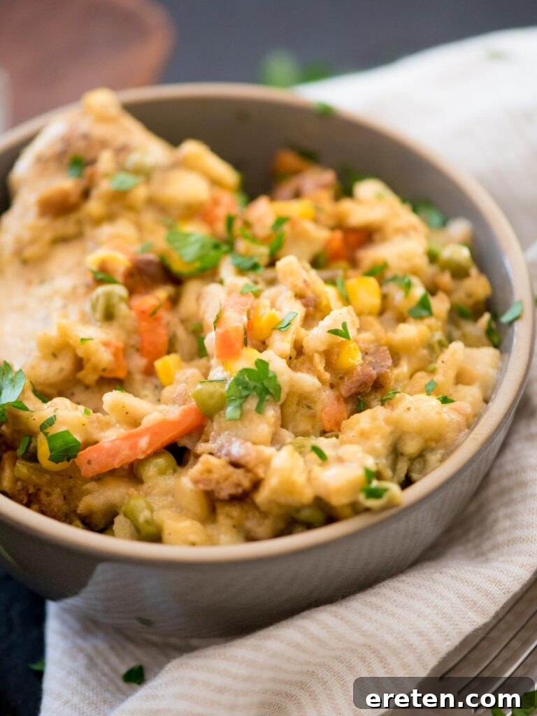 A close-up shot of the savory chicken and stuffing casserole, served in a bowl and adorned with freshly chopped parsley, highlighting its delicious texture.