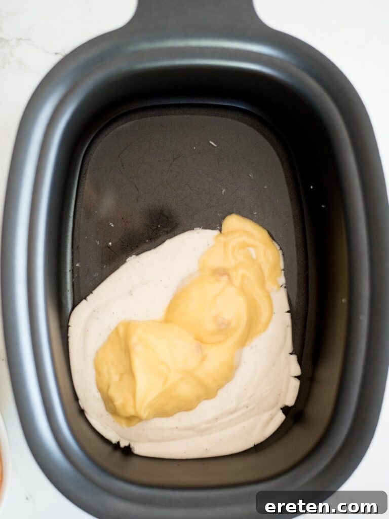 The creamy base of ranch dressing, water, and cream of chicken soup being whisked together in the slow cooker.