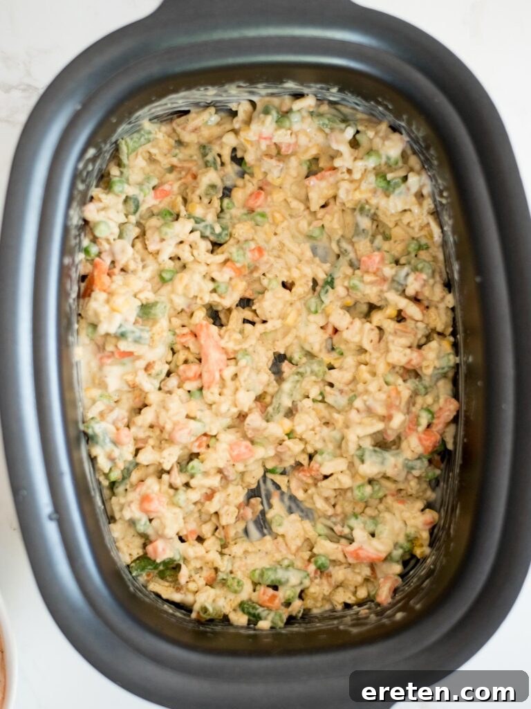 The stuffing mix, vegetables, and creamy sauce expertly combined and fully mixed within the crockpot.