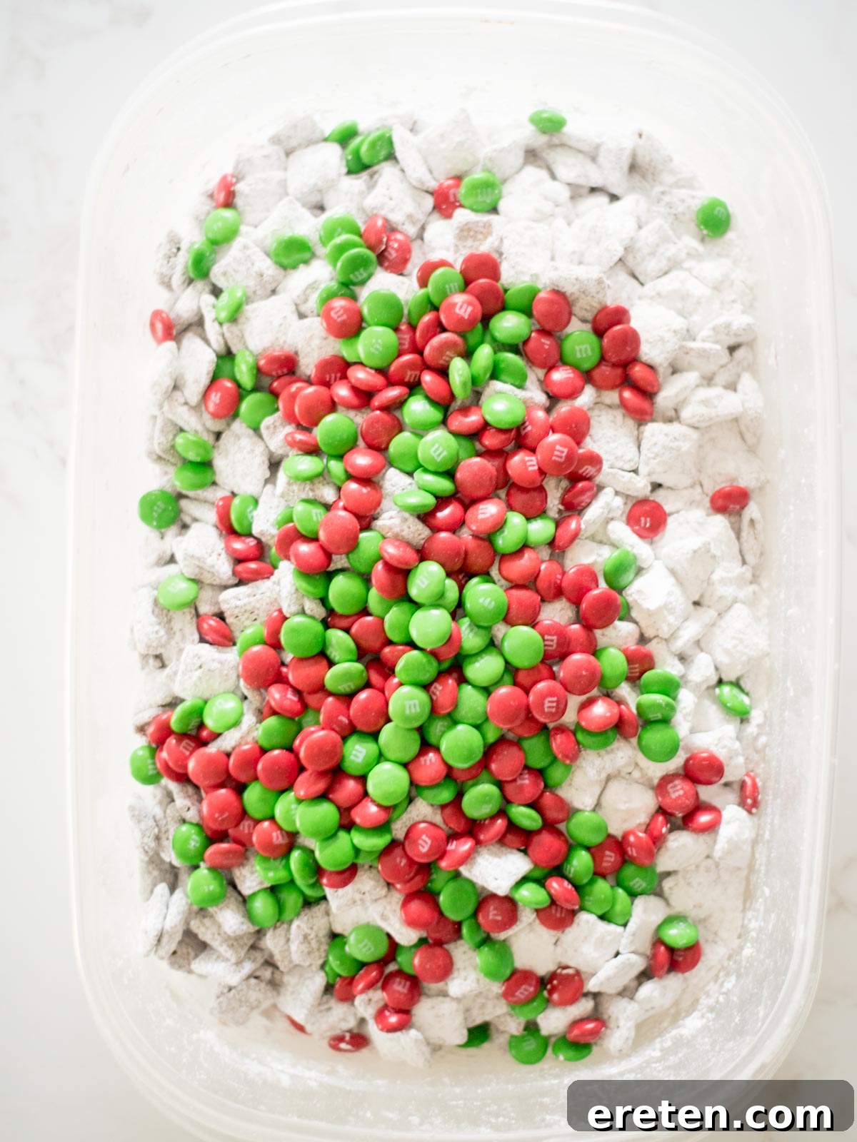 Festive Homemade Muddy Buddies 8 The final touch: vibrant green and red M&Ms mixed into the powdered sugar-coated muddy buddies, creating a festive display.