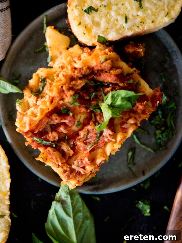 crockpot lasagna topped with fresh basil and a slice of garlic bread