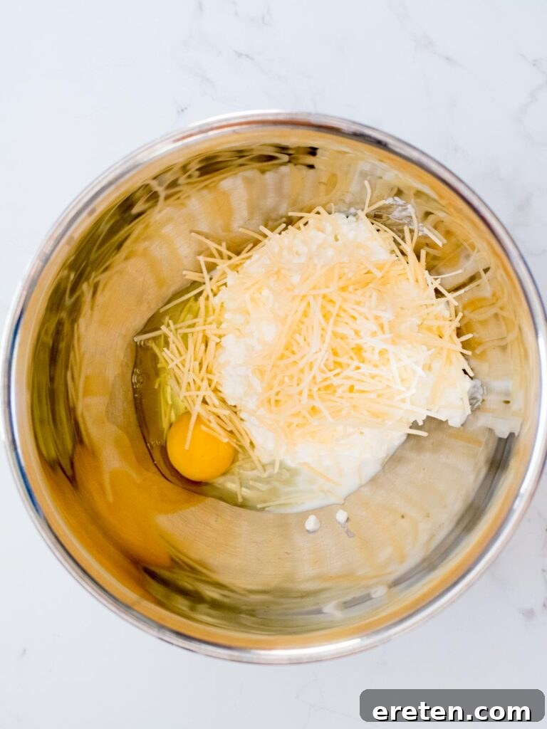 egg added to cottage cheese and parmesan in a mixing bowl