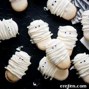 A stack of finished mummy cookies, showcasing their adorable candy eyes and white chocolate wraps.