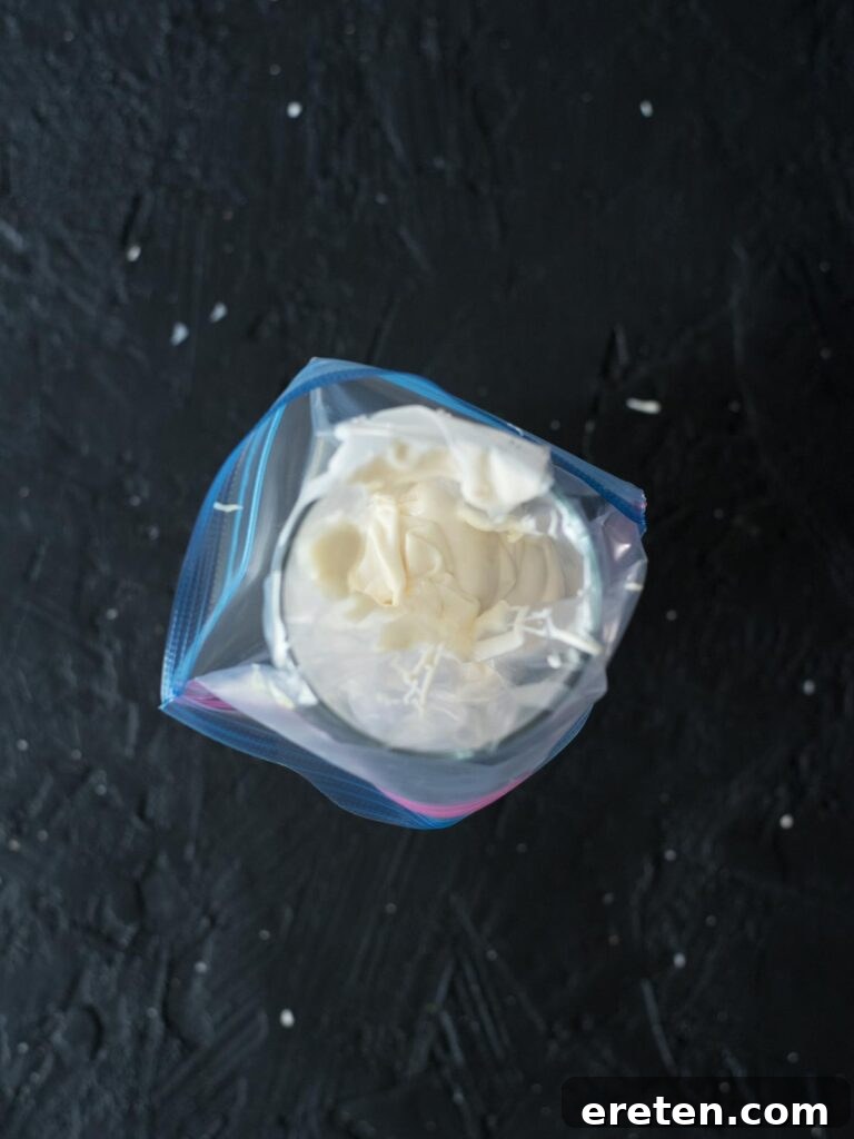 Melted almond bark poured into a ziploc bag within a cup