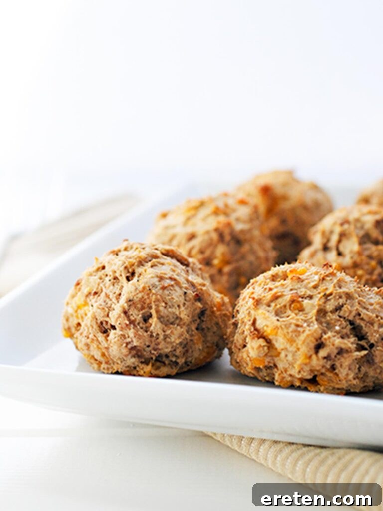 Bisquick Sausage Ball Bliss 3 Side view of lighter sausage balls sitting on a white serving plate, ready to be enjoyed as an appetizer.